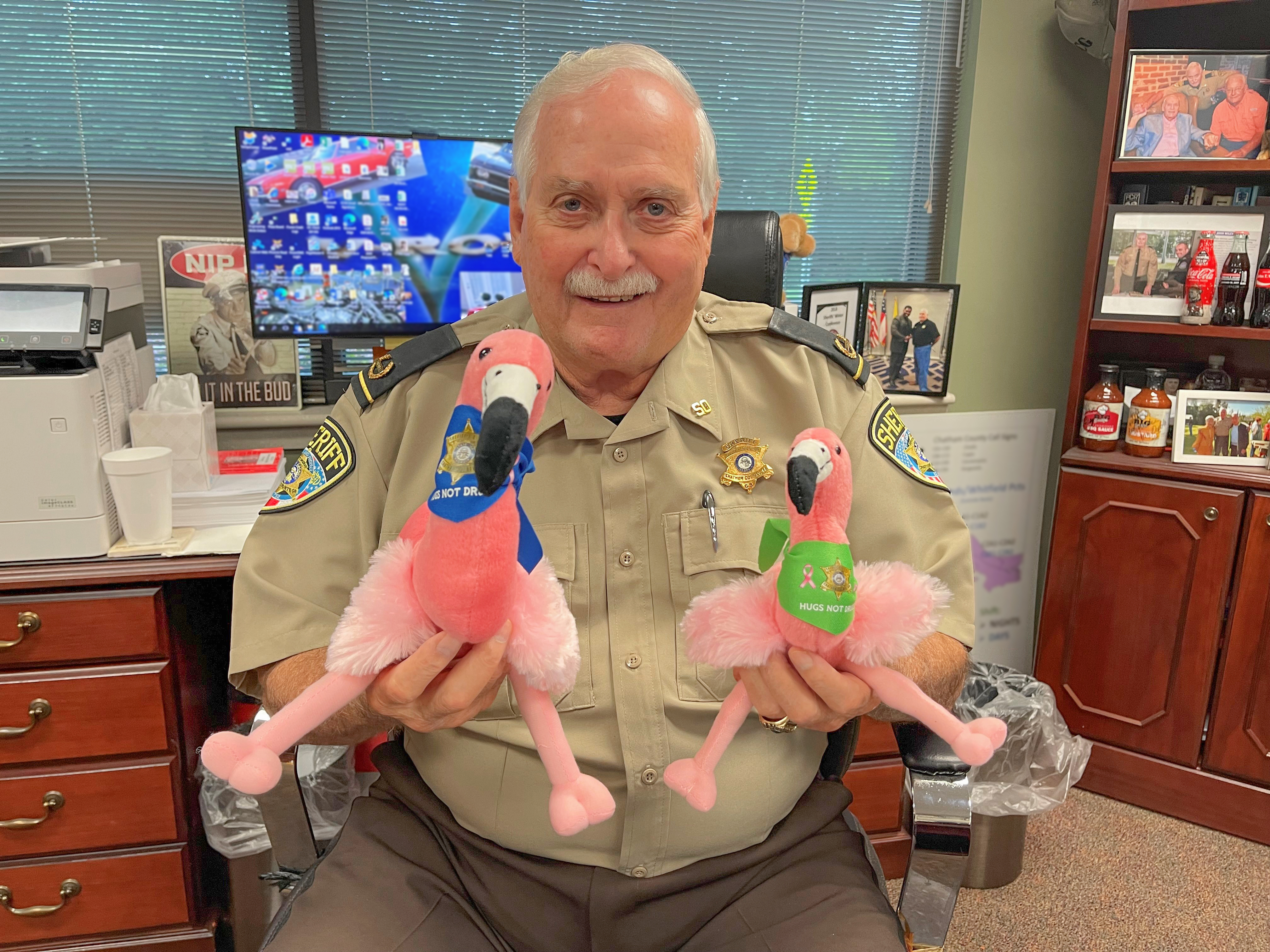 Sheriff holding plush flamingos